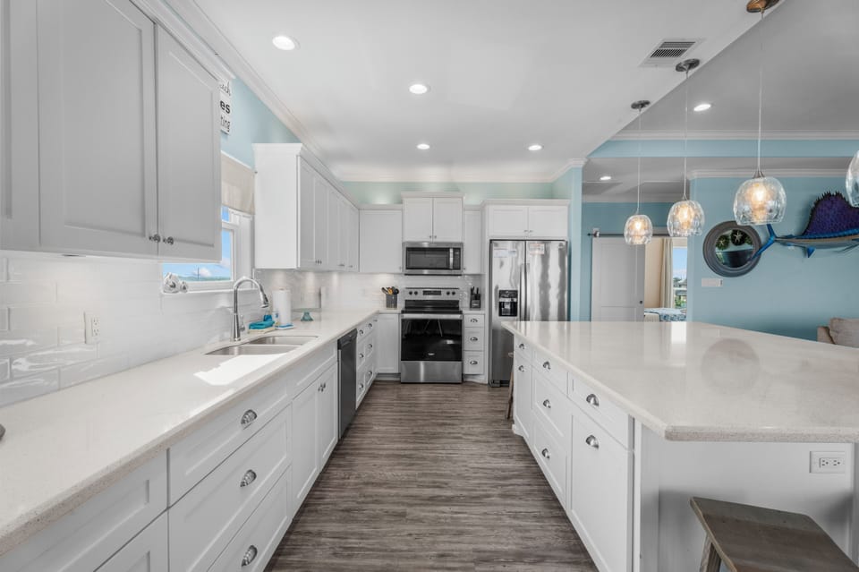 The bright kitchen features extensive counter space, abundant cabinetry, and modern appliances, creating a practical setting for preparing everything from quick snacks to group meals.