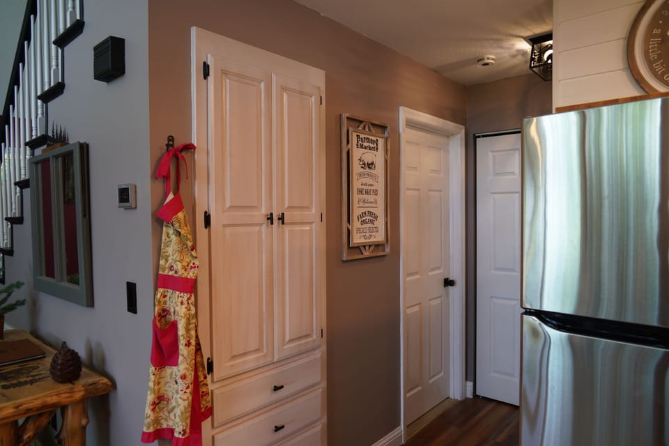 Kitchen pantry/storage area, door to downstairs bedroom, and doors to laundry.