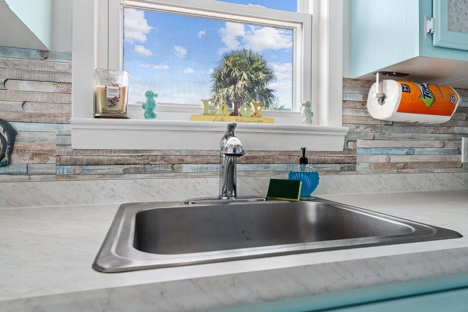 A bright window over the sink brings in natural light and adds to the airy, coastal feel.