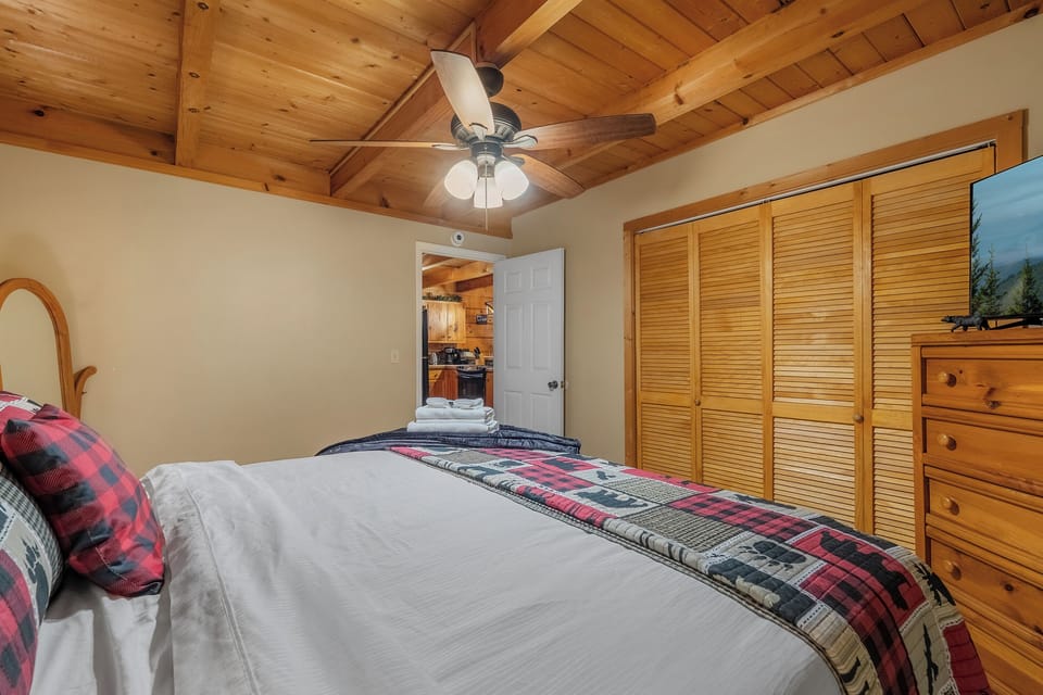 Ceiling fan, plaid bedding, and dresser space for a full week. Comfortable, warm, and set well back from the living areas for anyone turning in early.