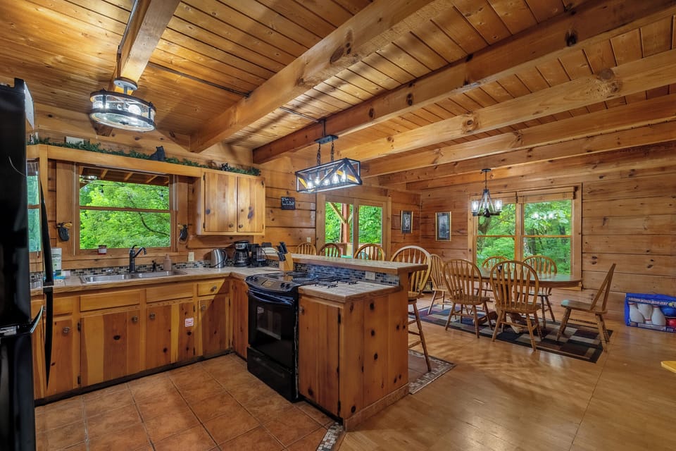 Open kitchen with bar seating and windows to the woods. Everything you need to cook in and skip the ninety-minute restaurant wait in Pigeon Forge tonight.