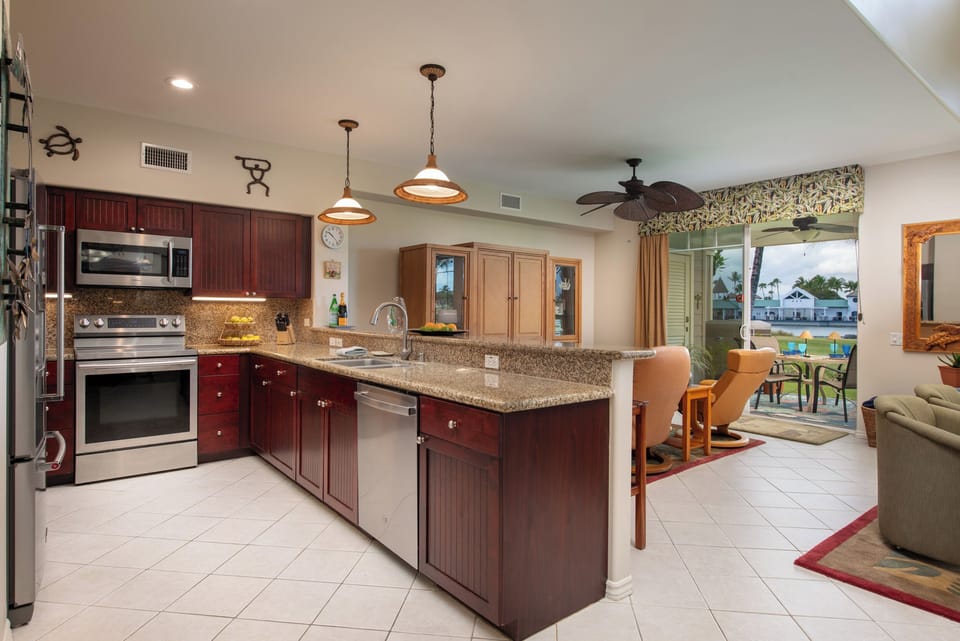 Step into your fully equipped kitchen with granite countertops and stainless appliances, flowing seamlessly to your living space. The open layout invites you to cook and relax while enjoying tropical breezes through your patio doors.