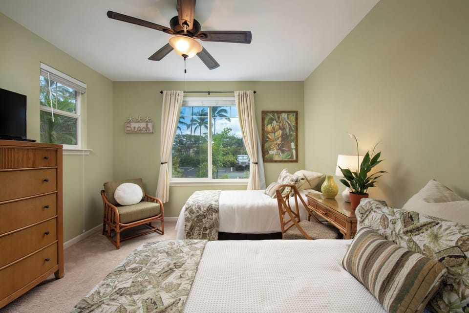 Relax in your peaceful tropical retreat with two comfortable beds, soft island breezes from the ceiling fan, and natural light flooding the calming green space.
