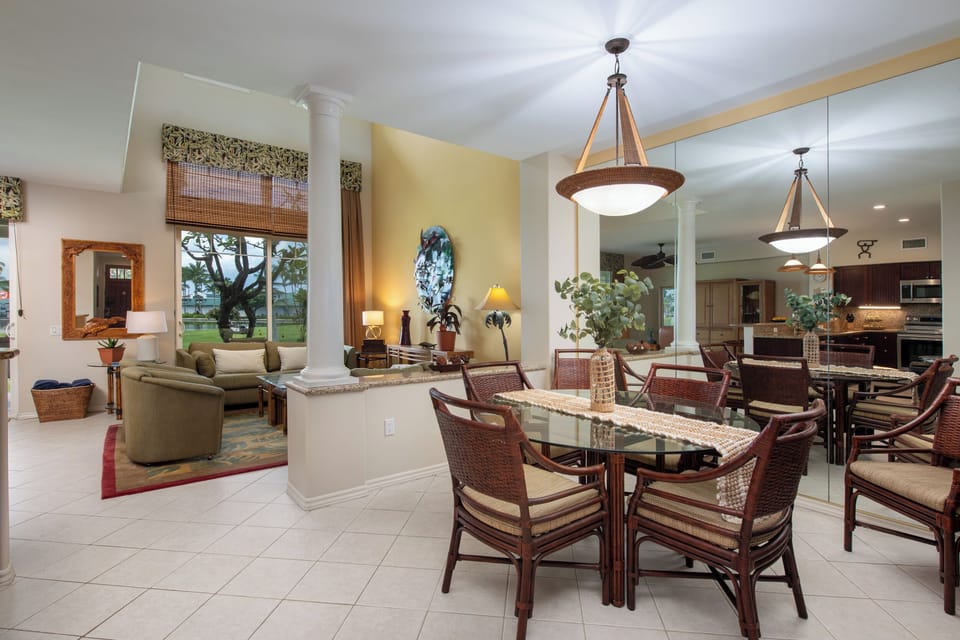 Gather around the elegant dining table where natural light pours through palm-framed windows, opening onto a breezy living space perfect for your island getaway.