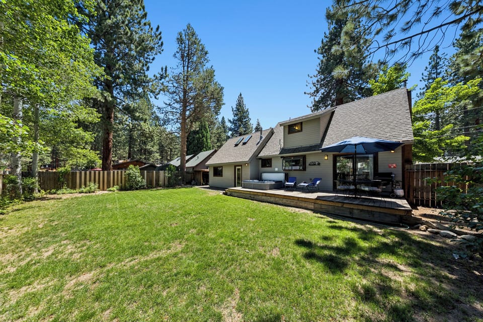 A charming mountain retreat nestled among towering pines, offering a spacious backyard and covered deck surrounded by natural beauty—perfect for peaceful mornings and starlit evenings.