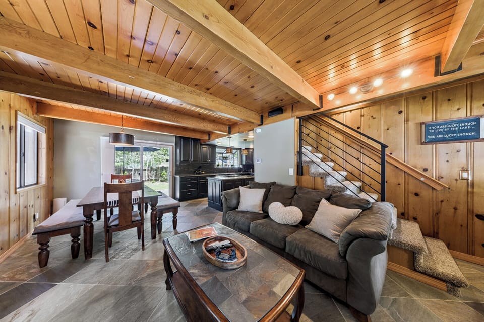 Relax in your inviting open-concept living space, where warm wood beams and cozy seating blend seamlessly with a full kitchen and dining area—perfect for unwinding after your adventures.