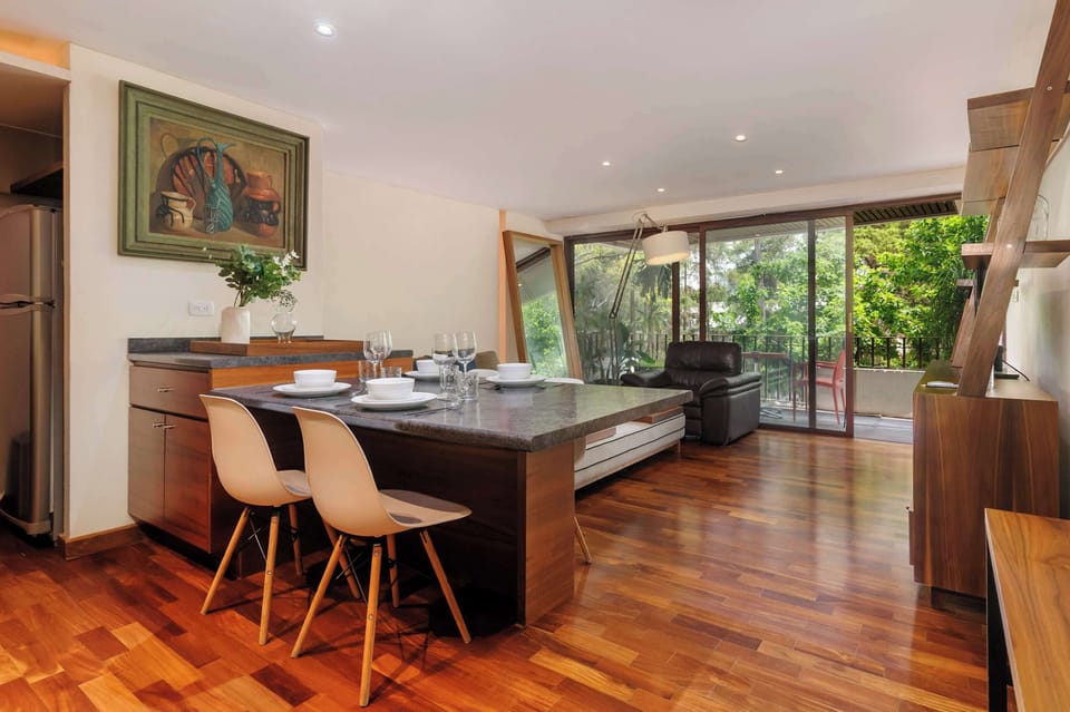 Bright dining area with a stylish table, comfortable seating, and large windows overlooking the greenery.