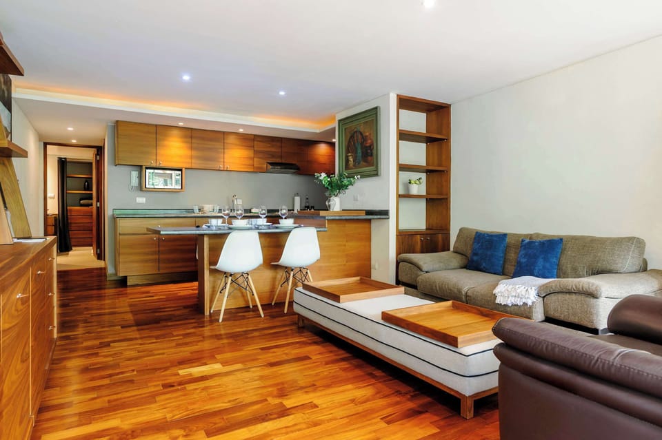 Open living and kitchen space featuring warm wood finishes, a comfortable seating area, and a fully equipped kitchen.