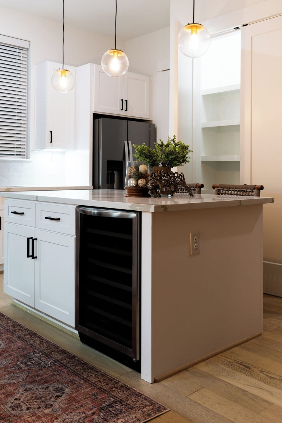 Bright modern kitchen with island, wine fridge, and elegant pendant lighting