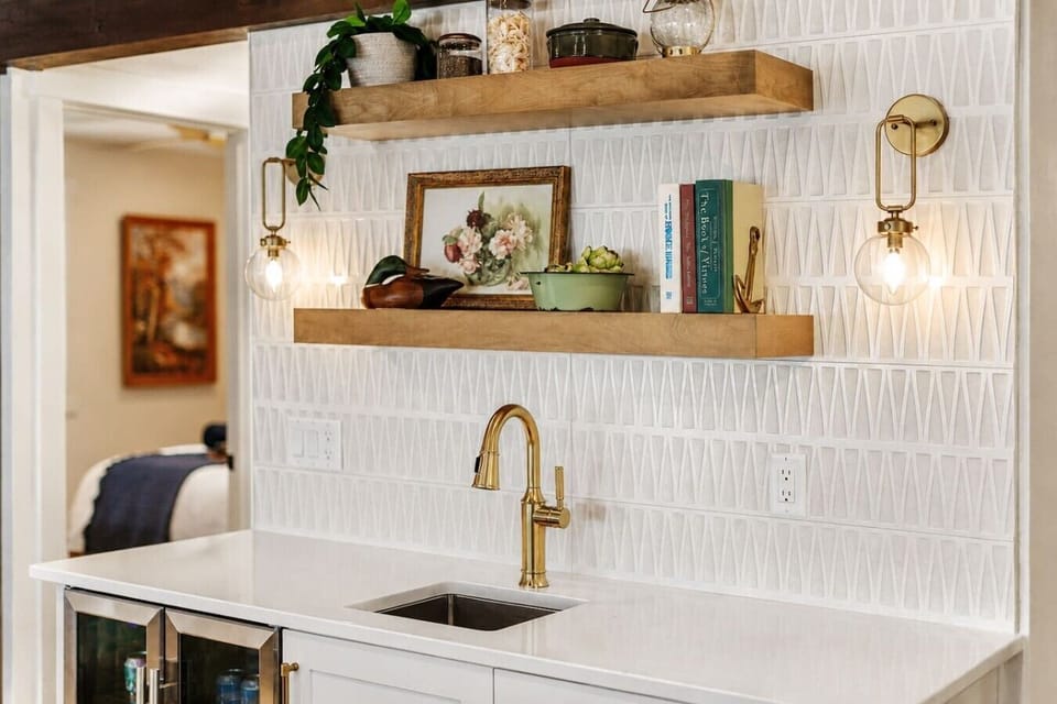 The kitchen wet bar pairs a sink and beverage refrigerator with open shelving and convenient counter space.