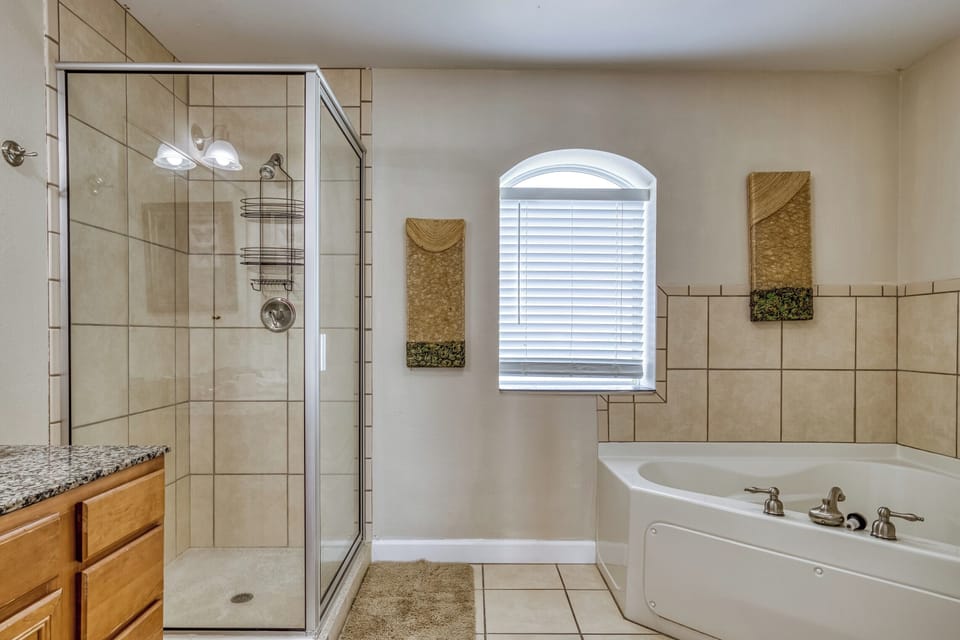 Bathroom, jetted tub.  granite countertop. tile floor.  art.  window. shower.