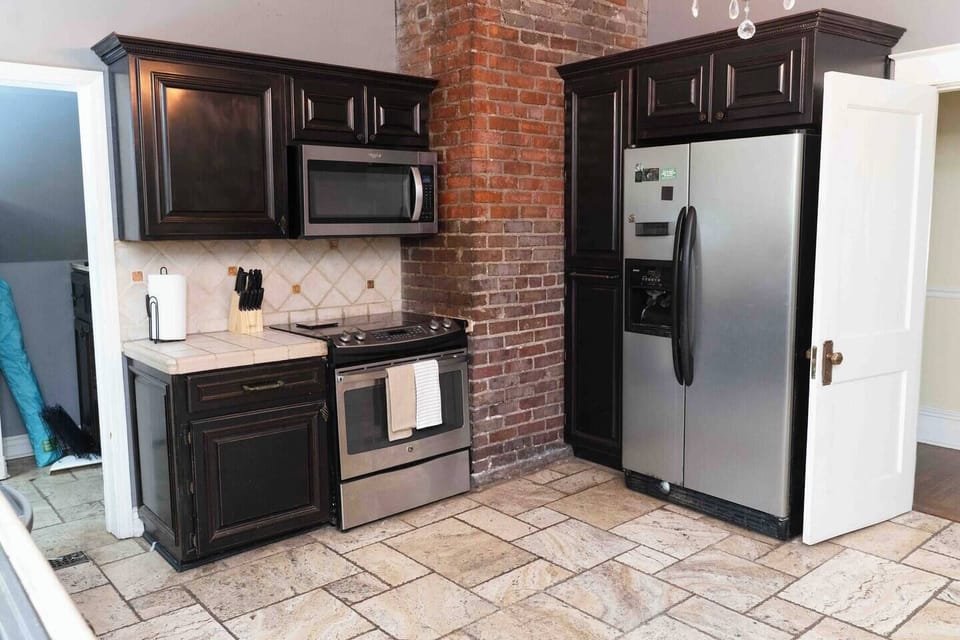 Stainless refrigerator and range against original exposed brick