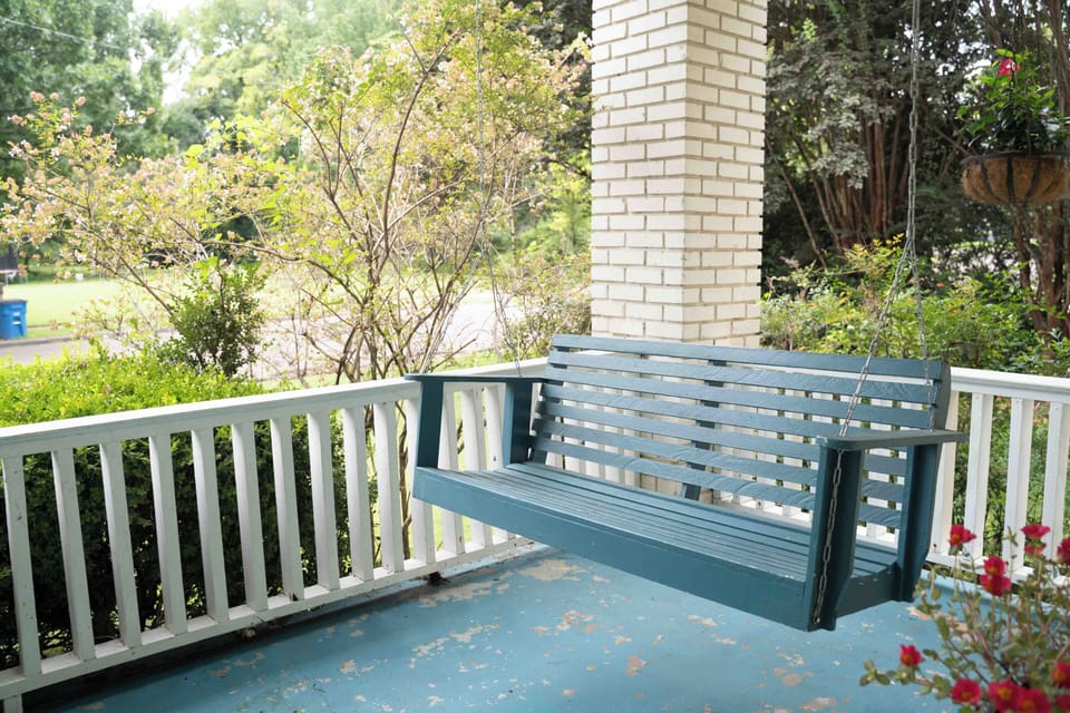 Relax on the charming front porch swing surrounded by lush greenery