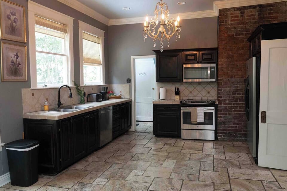 Full kitchen under a chandelier, with exposed brick and room to spread out