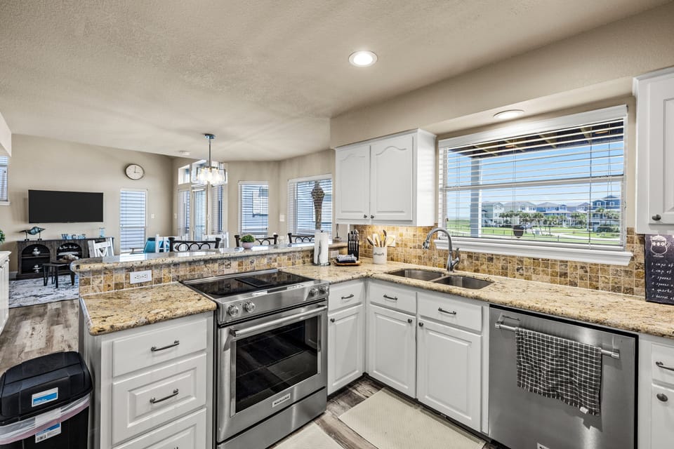 Bright, designer-renovated kitchen with granite countertops, stainless-steel appliances, generous workspace, and an open view into the living and dining areas. Enjoy Gulf views from the kitchen window.