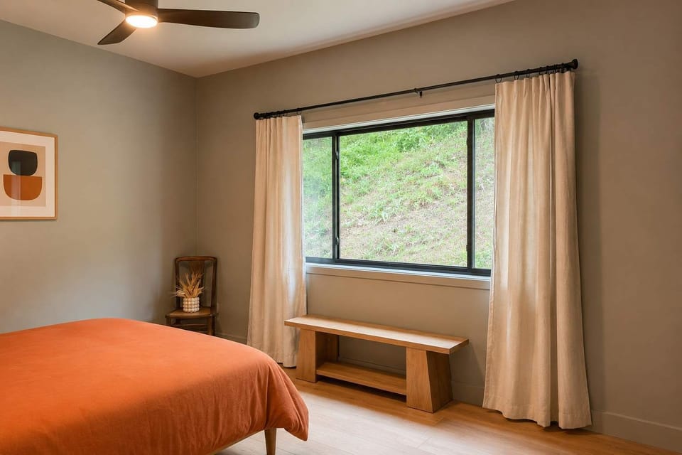 Queen bedroom suite, highlighting the natural light from wide windows with full-length drapes.
