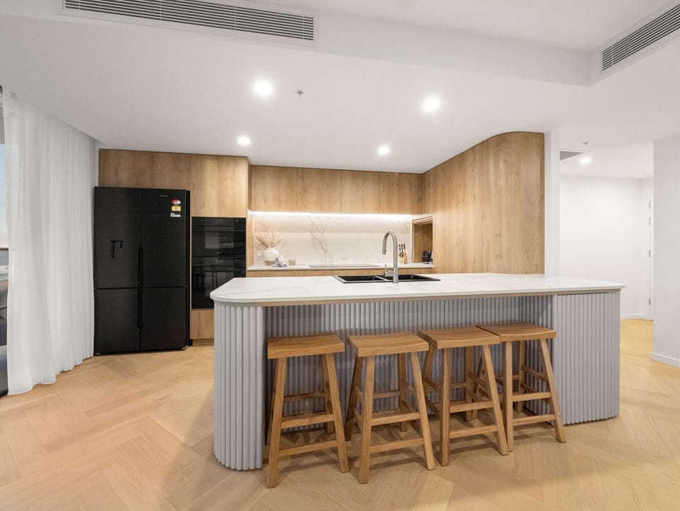 Fluted island, oak joinery and a stone benchtop, with seating for four.