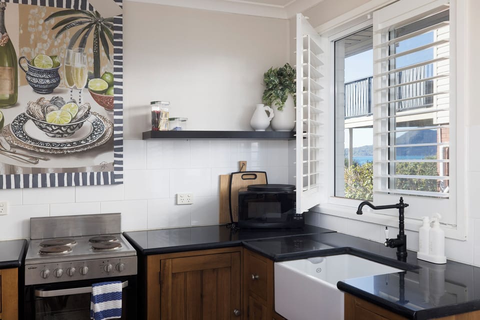 Bright kitchen with farmhouse sink, shutters, and lovely water views