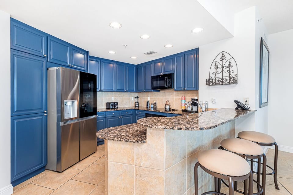 Picture yourself preparing meals in this spacious kitchen with its striking blue cabinetry, granite countertops, and breakfast bar seating—your perfect space for cooking and gathering.