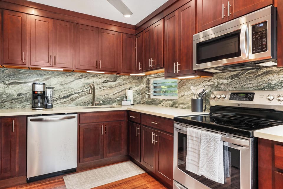 Step into your fully equipped kitchen featuring rich cherry cabinets, gleaming granite counters, and stainless appliances. Everything you need to cook your favorite meals awaits.