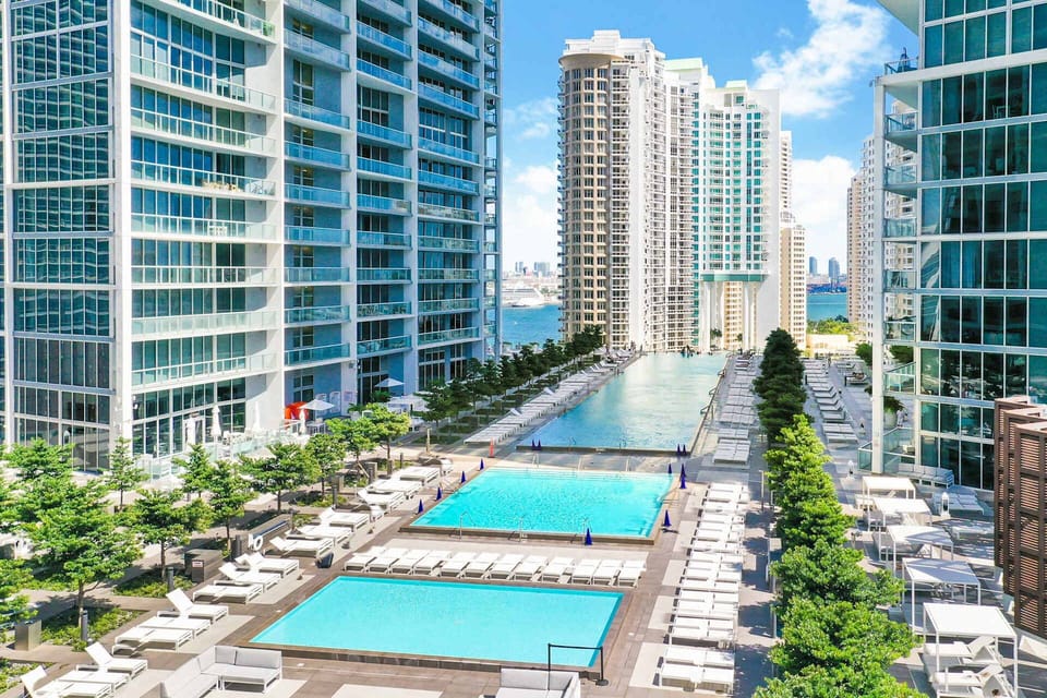 Resort-style pool deck with multiple sparkling pools, comfortable lounge seating, and a vibrant city backdrop. The perfect place to soak up the sun, unwind poolside, or enjoy a refreshing swim during your stay.
