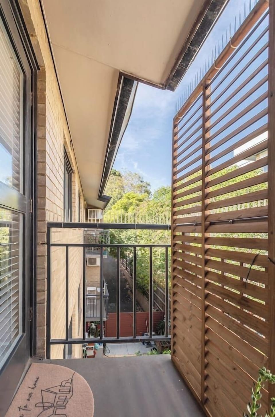 Step onto your private balcony, framed by timber slats and greenery—an inviting spot to enjoy fresh air.