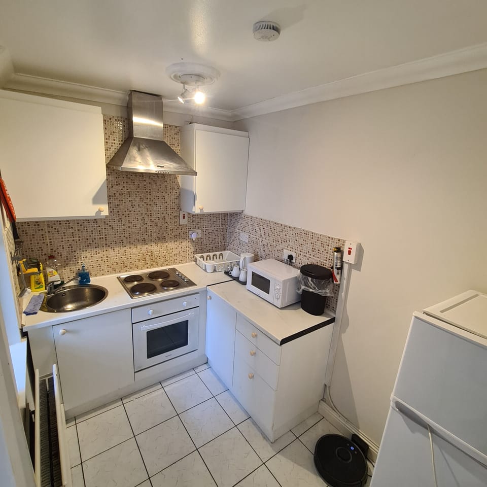 Bright, compact kitchen with oven, stovetop, microwave, and modern backsplash