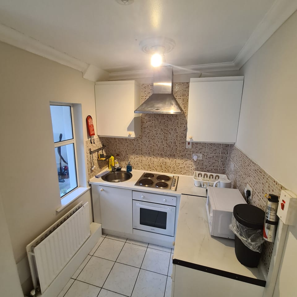 Bright compact kitchen with oven, cooktop, microwave, and washer