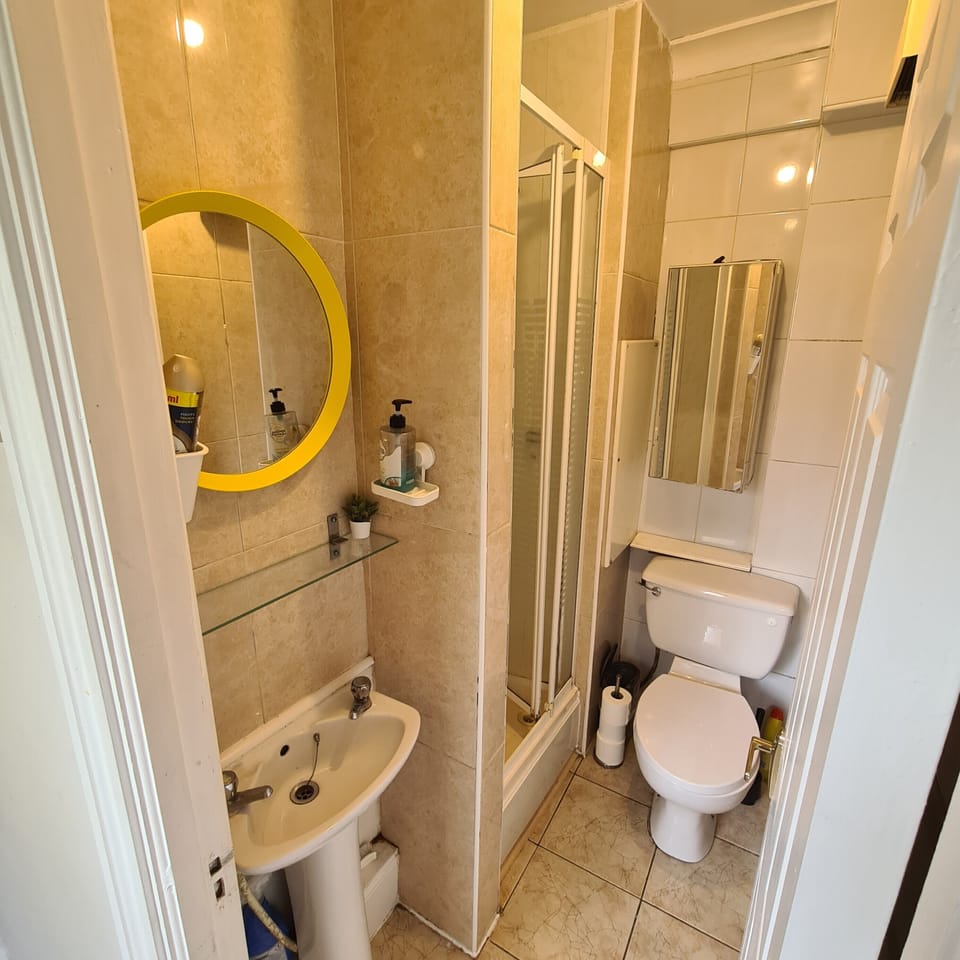 Bright tiled bathroom with glass shower and warm, modern finishes