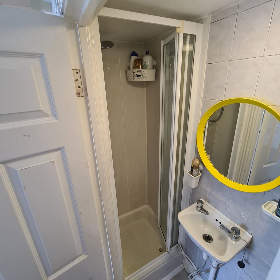 Compact bathroom with walk-in shower and bold yellow mirror