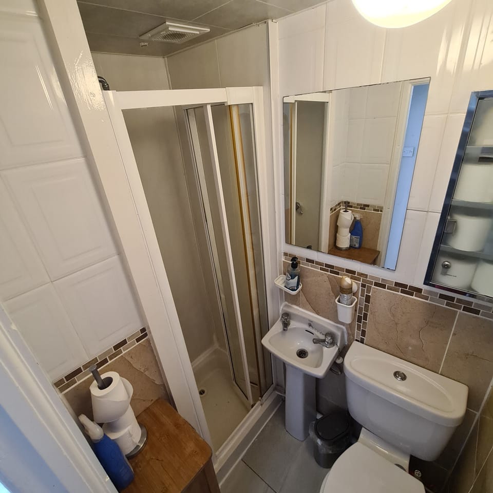Compact tiled bathroom with glass shower and handy guest essentials