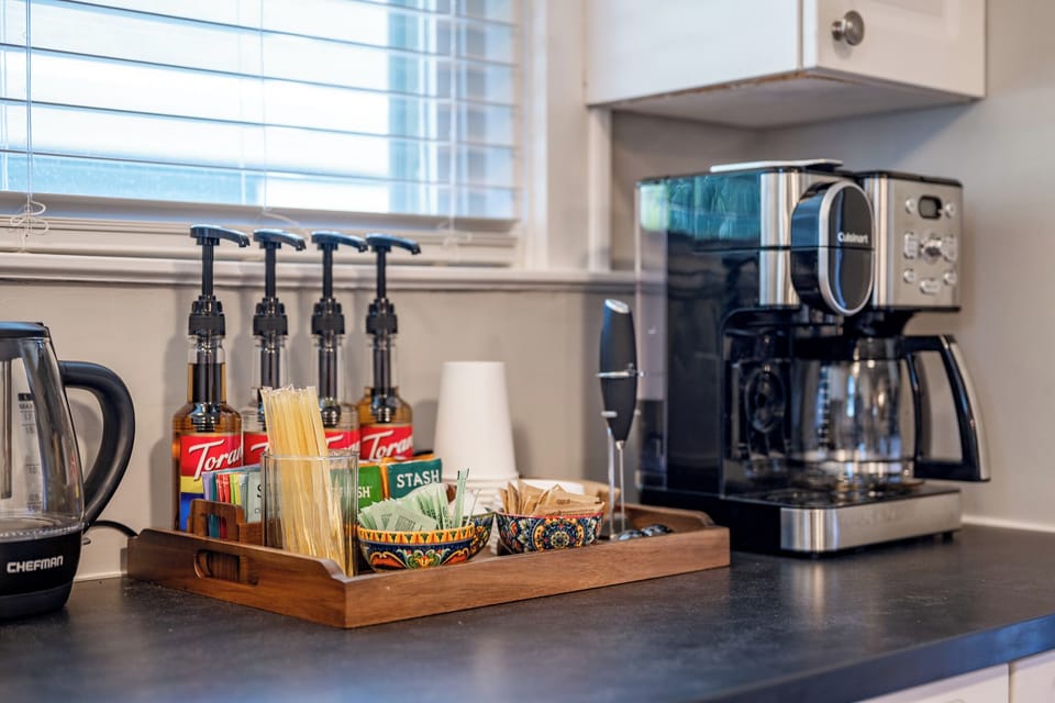 Guest-ready coffee & tea station with brewer, kettle, syrups, and supplies