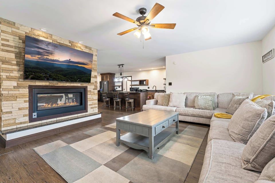 Open living area with a stone fireplace, smart TV, and pool table