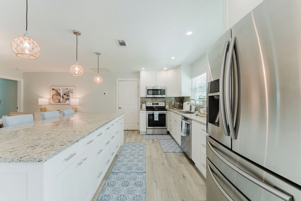 Cook, gather, and entertain in this fully equipped chef's kitchen featuring an oversized quartz island with seating, stainless steel appliances, and abundant prep space—all flowing seamlessly into the home's open-concept living areas.