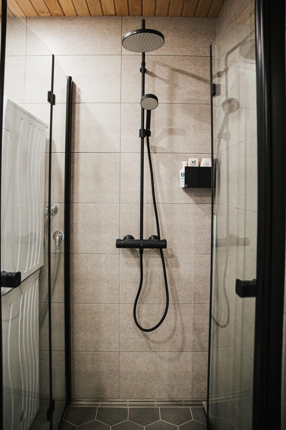 A sleek walk-in shower with modern black fixtures and clean tiling.