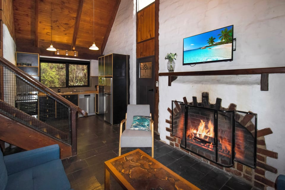 Cozy cabin-style living with fireplace, vaulted ceilings, and modern kitchen