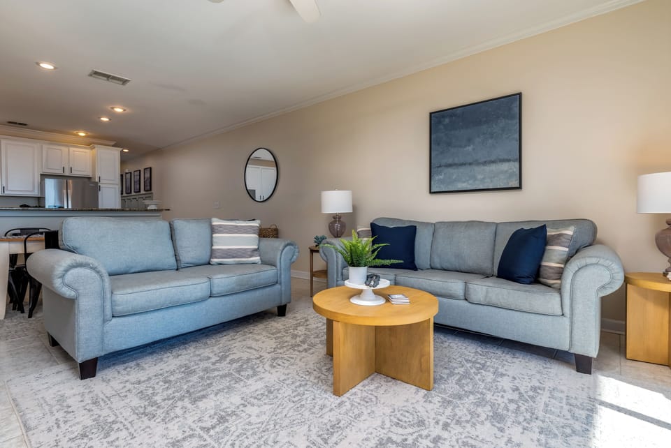 Sink into plush gray sofas in your open-concept living space, where natural light flows through and connects to your fully equipped kitchen.