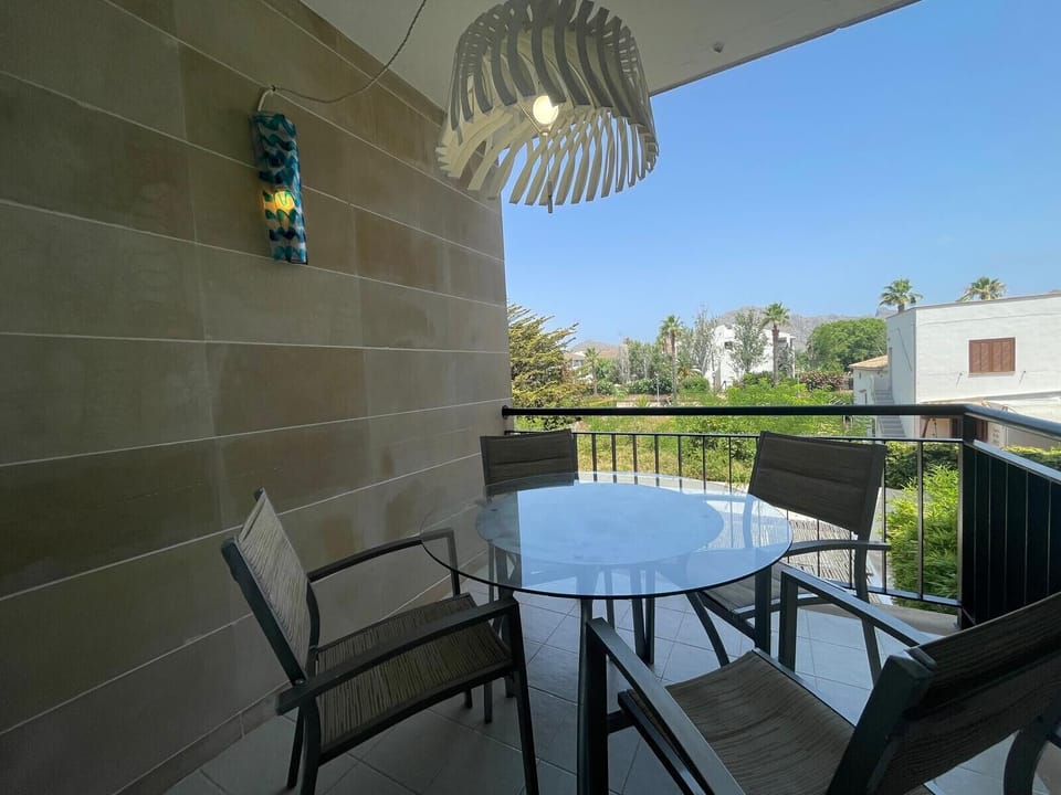 Covered private terrace with outdoor dining table for four, offering open views of the gardens and mountains, perfect for al fresco dining.