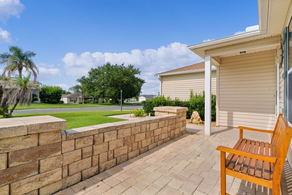 A peaceful residential neighborhood with palm-lined streets and a private patio area featuring comfortable seating and tropical landscaping.