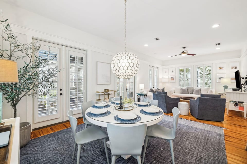 Gather around your elegant dining table where natural light streams through shuttered windows, creating the perfect setting for memorable meals.