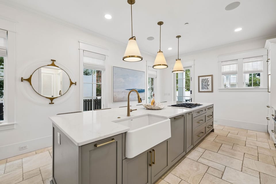 Picture yourself preparing meals in this elegant kitchen, where warm pendant lights and charming brass fixtures create a welcoming ambiance for your culinary adventures.