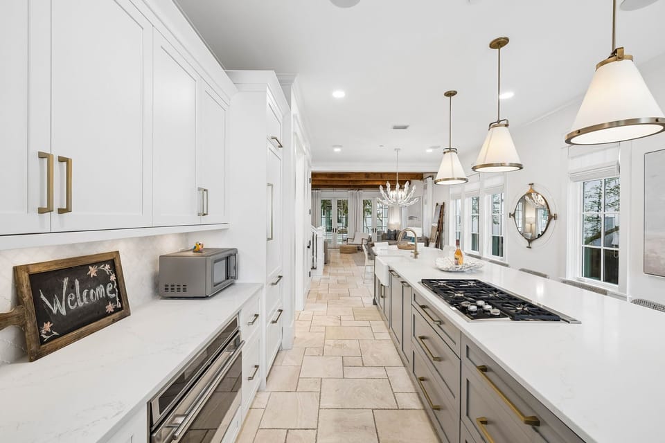 Step into your dream kitchen with gleaming white cabinetry, elegant brass fixtures, and a chef's cooktop ready for your culinary adventures.