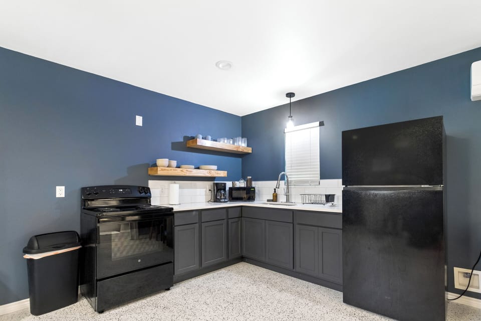 Modern kitchenette with coffee station, open shelving, and sleek finishes
