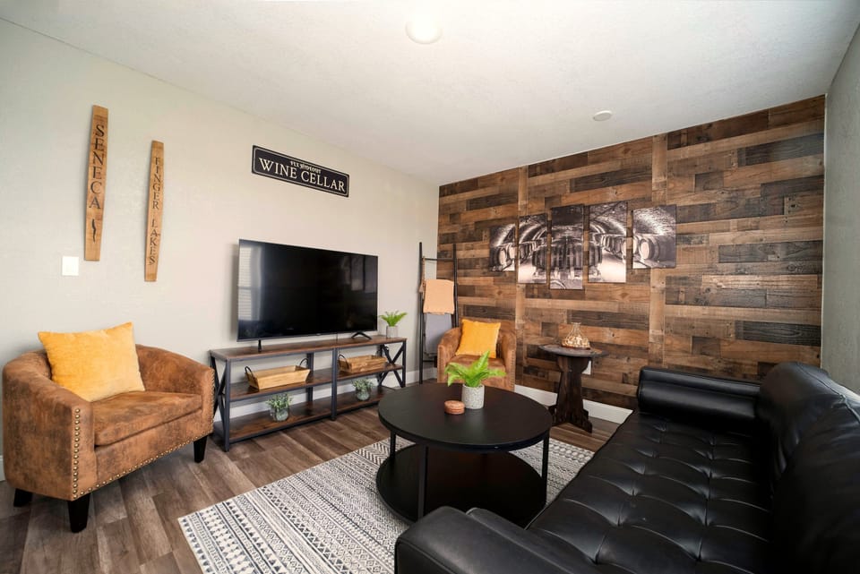 Cozy rustic lounge with accent wall, comfy seating, and big-screen TV