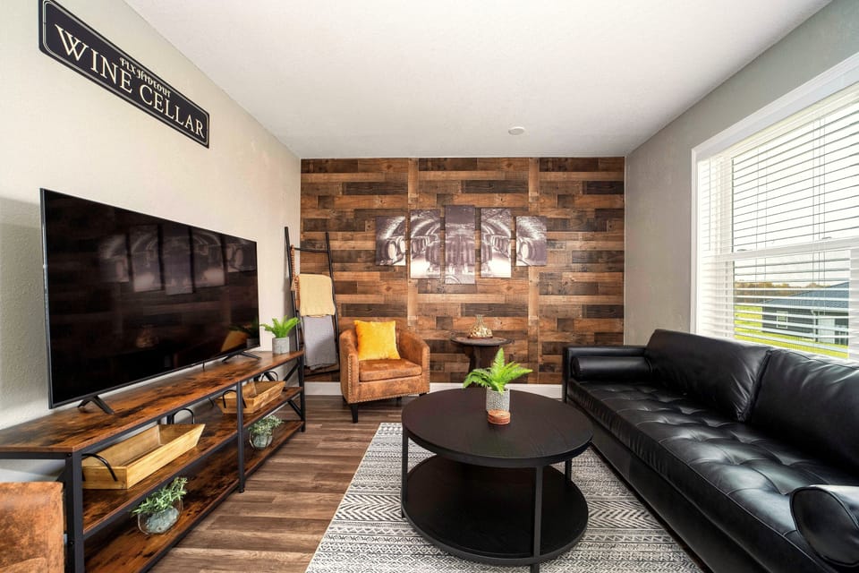 Rustic-modern lounge with accent wall, smart TV, and bright natural light