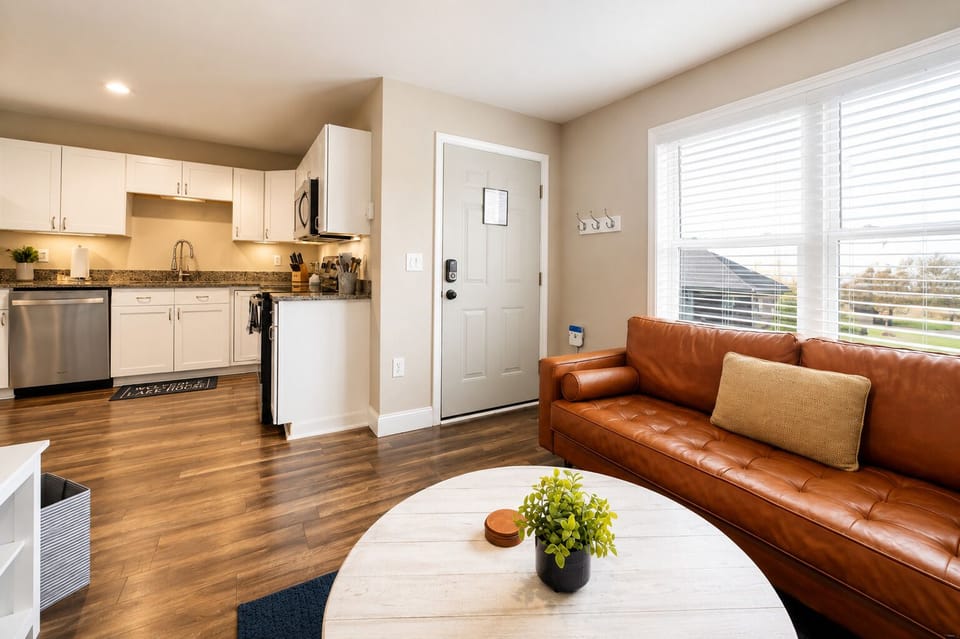 Bright open living room and full kitchen with leather sofa and natural light