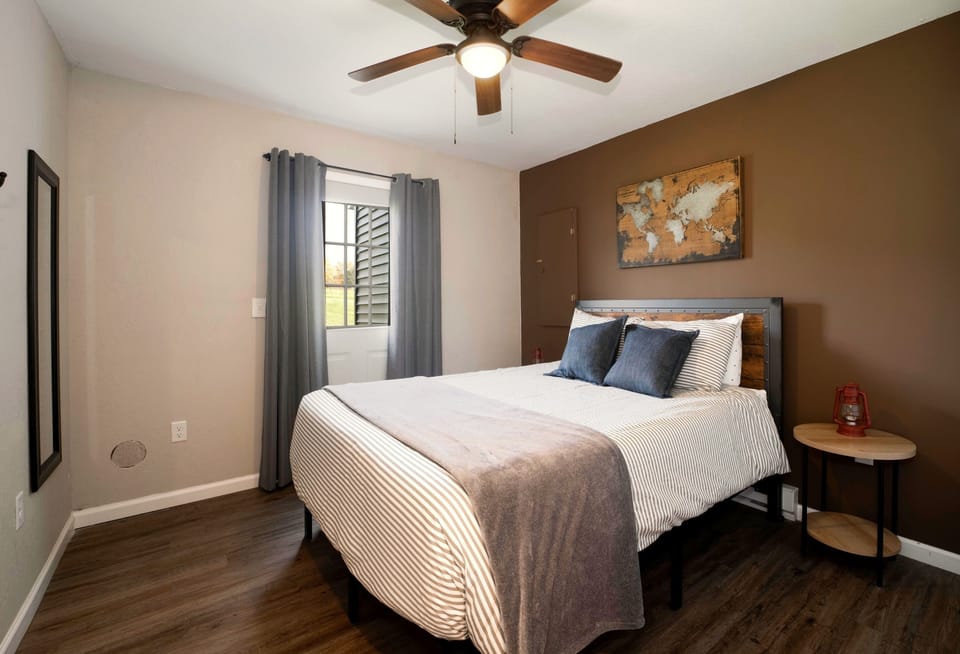 Cozy queen bedroom with warm decor, ceiling fan, and stylish accent wall