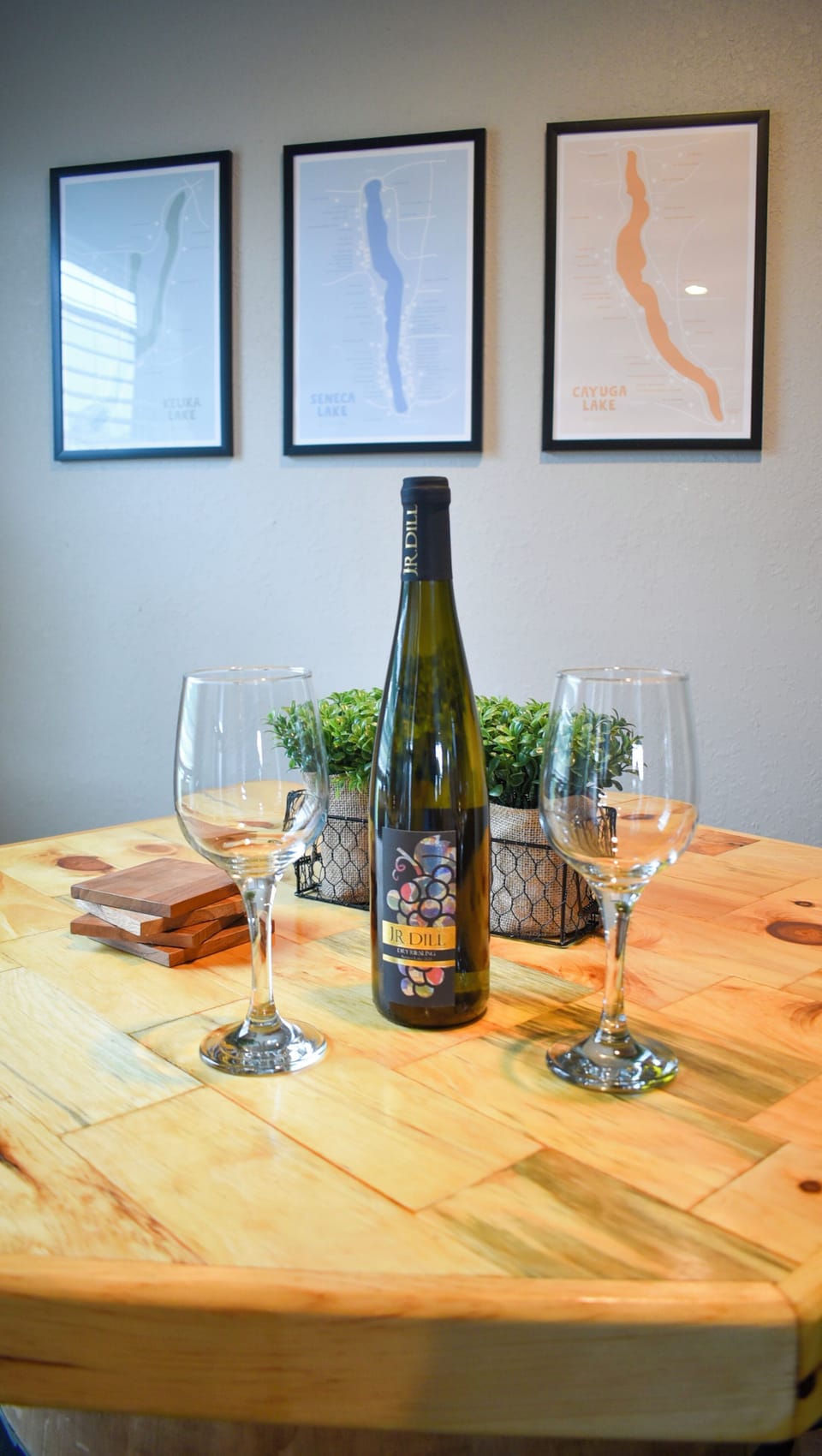 Cozy tasting nook with wine, lake-inspired art, and a warm wood table.