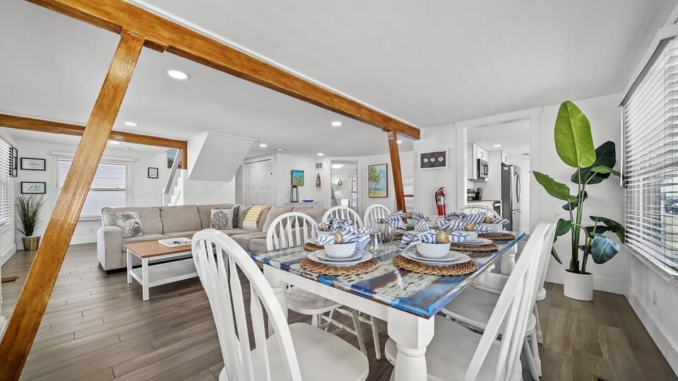 Bright open dining and living space with rustic beams and coastal charm