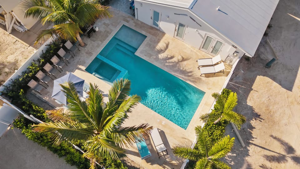 Private tropical pool oasis with spa, loungers, and sunny resort-style deck